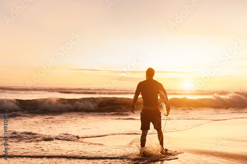 A man is standing with a surf in his hands on the sea shore.