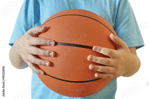 young basketball player. the boy holds a basketball in his hands. blue t-shirt orange ball. white background isolate.