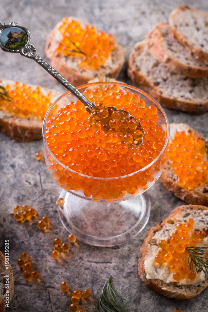 Delicious bright red fresh snack red caviar on a wooden background. Silver spoon with caviar. Expensive luxury delicacy seafood. Delicious bright red fresh snack red caviar on a wooden background. Silver spoon with caviar. Expensive luxury delicacy seafood.
