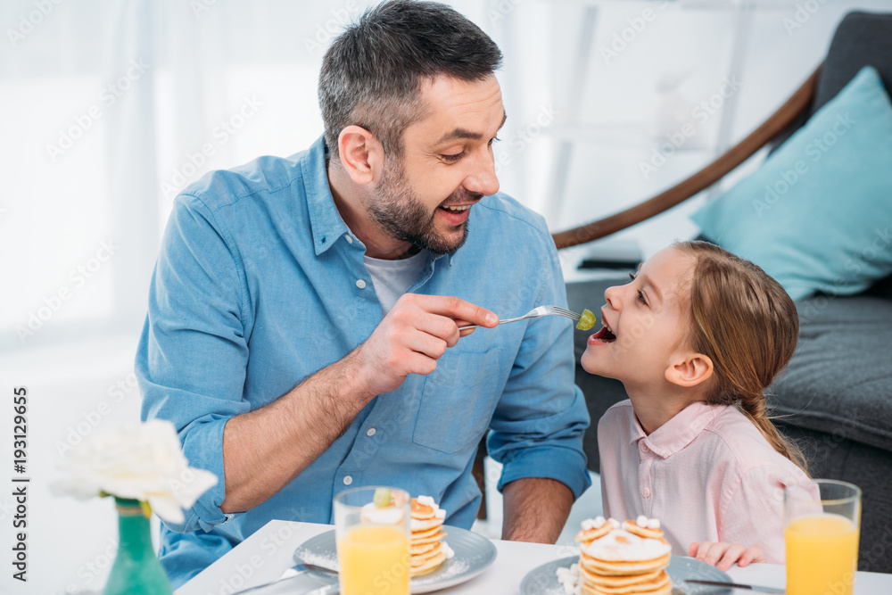 happy father and little daughter having breakfast at home happy father and little daughter having breakfast at home