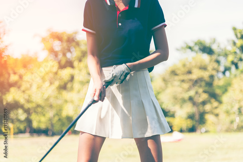 Young female golf player on course, women practice golf playing outdoor, green grass.