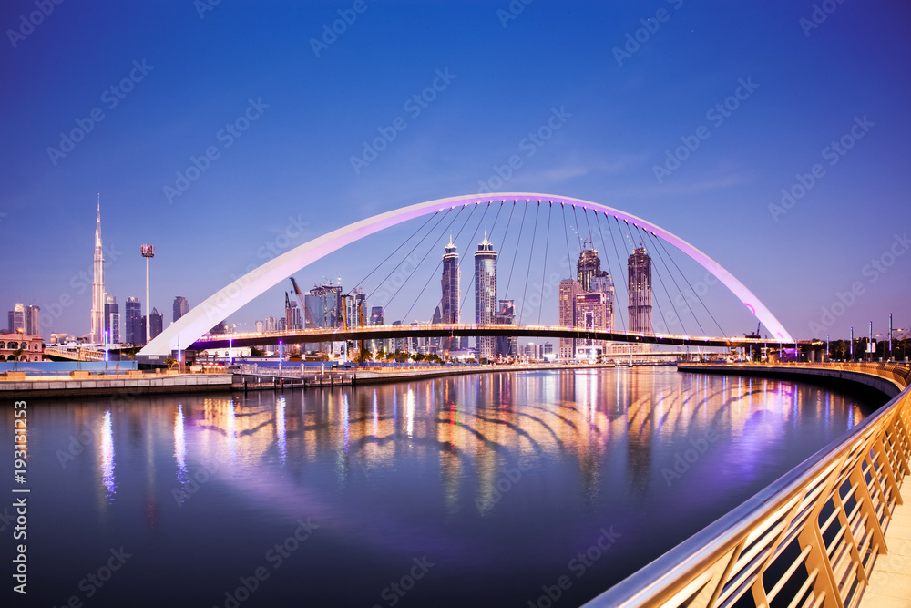 Fototapeta premium Dubaj, Zjednoczone Emiraty Arabskie - luty 2018: Kolorowy zachód słońca nad drapaczami chmur w centrum Dubaju i nowo wybudowanym mostem tolerancji, patrząc z kanału wodnego w Dubaju.
