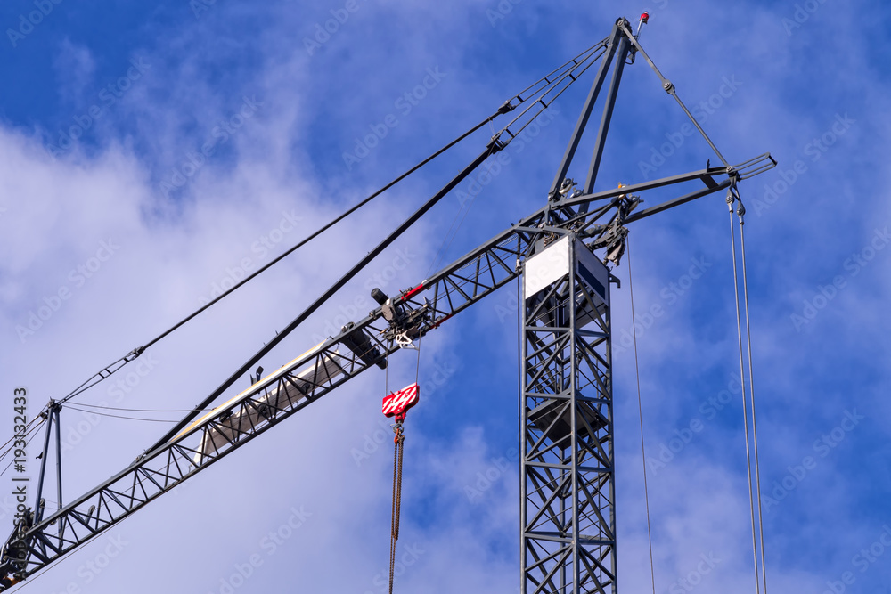 Gray tower crane against the cloudy blue sky