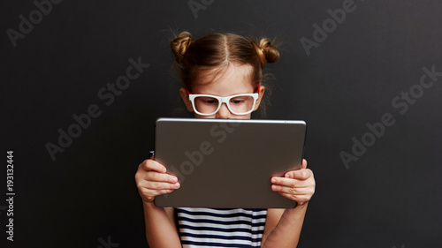 Cute child with digital tablet. Portrait of pretty little girl using web app for education. 