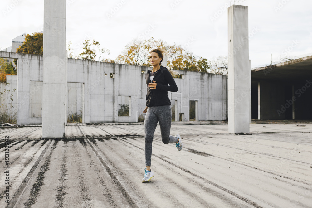 Young fit woman running in the industrial urban zone, side view of fitness girl running Young fit woman running in the industrial urban zone, side view of fitness girl running