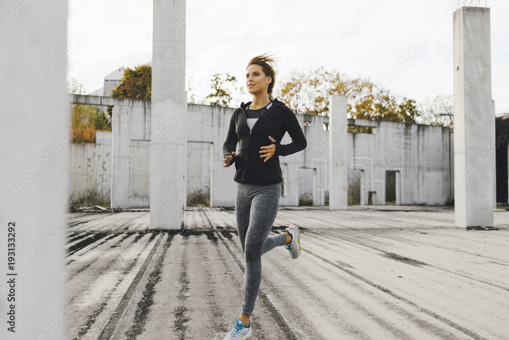 Young fit woman running in the industrial urban zone, side view of fitness girl running Young fit woman running in the industrial urban zone, side view of fitness girl running