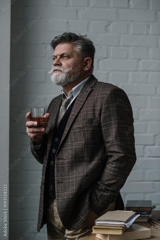 senior man in tweed suit with glass of whiskey looking away senior man in tweed suit with glass of whiskey looking away
