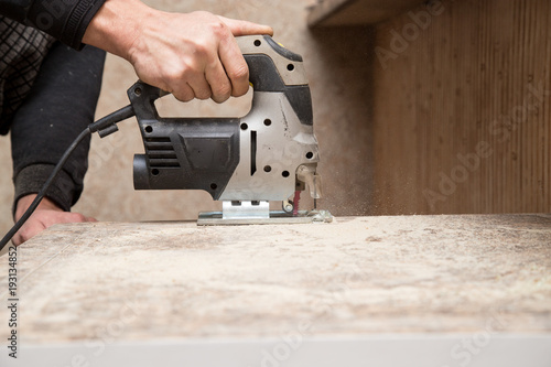 Master cuts wood with a jig saw