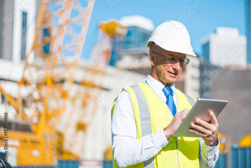 Construction manager controlling building site and tablet device in his hands