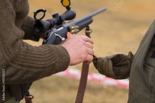 soldier give ammo to sniper, close up picture of rifle reloading 