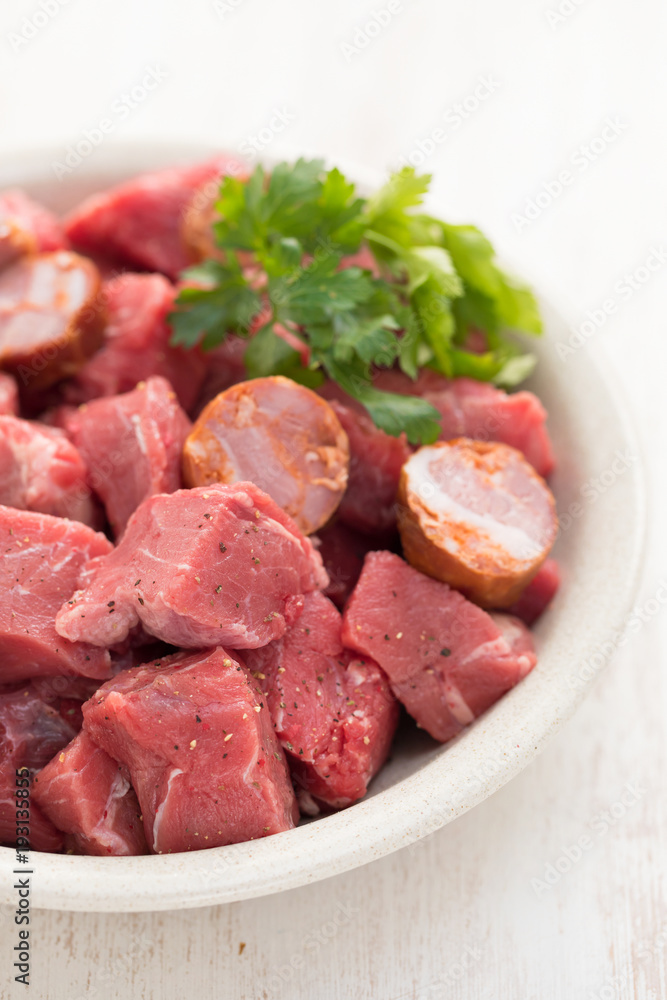 raw meat with smoked sausages on plate raw meat with smoked sausages on plate