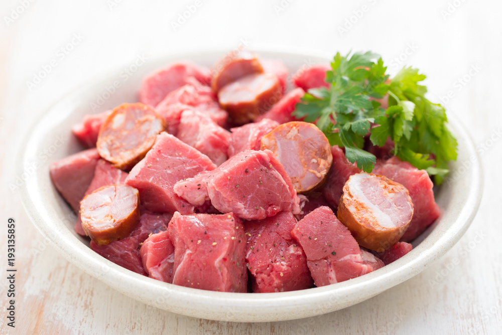 raw meat with smoked sausages on plate