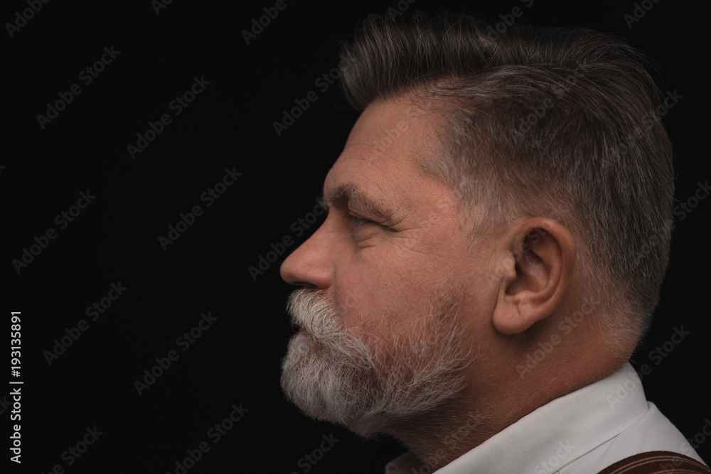 Obraz premium side view of senior man with stylish beard isolated on black
