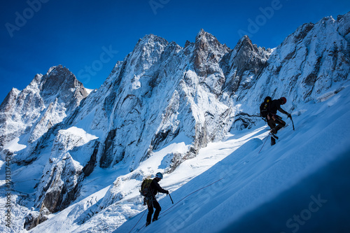 Young man climbing up on glacier in big mountain, massive Mont Blanc, Chamonix