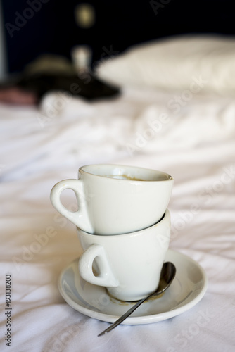 empty cups of coffee on an unmade bed