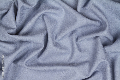 Blue woolen crumpled wrinkled fabric with waves, background crumpled tissue.