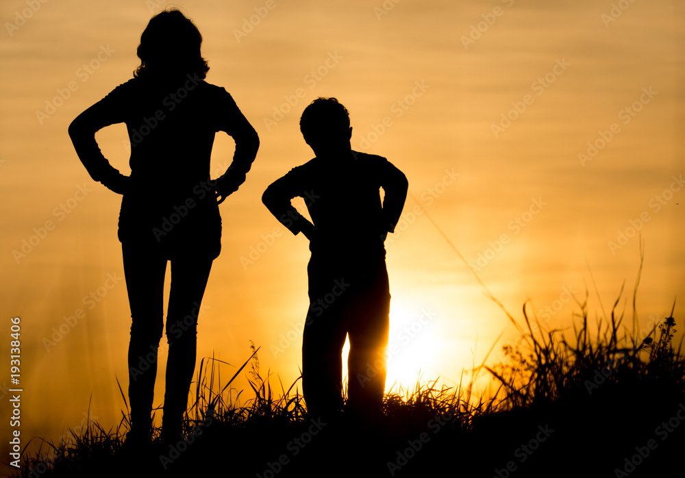 Silhouette of Mom and son in the rays of sunset