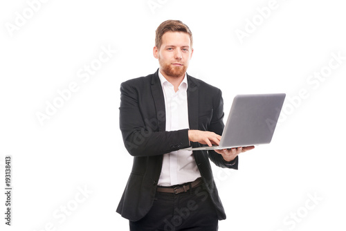 Studio portrait of young manager in suit holding open laptop