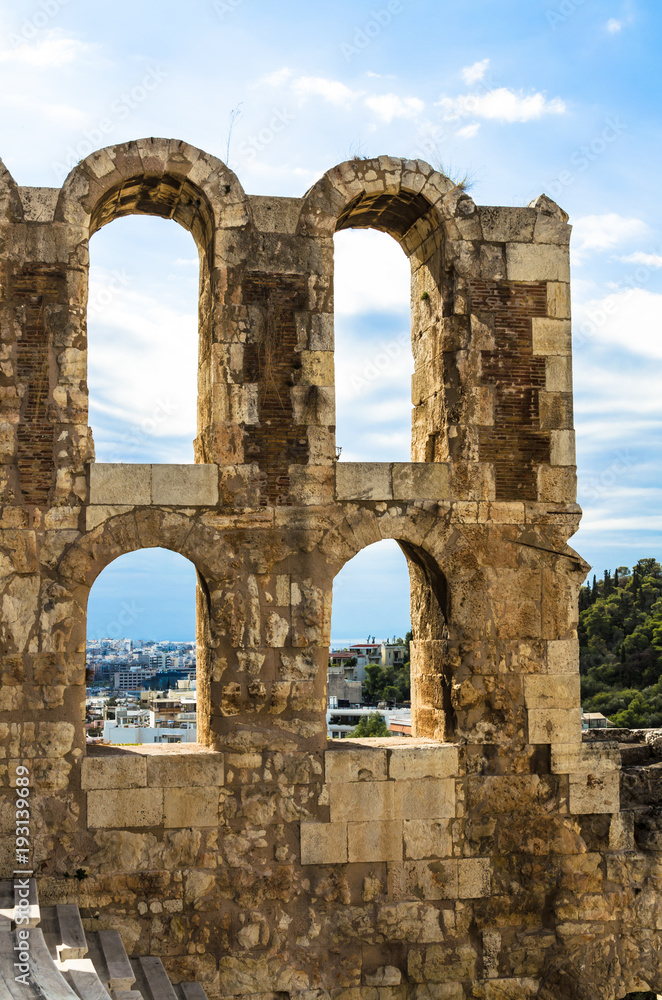 View from the Acropolis to the Ruins of ancient theater Odeon of Herodes Atticus, in the background: modern buildings of Athens, Greece