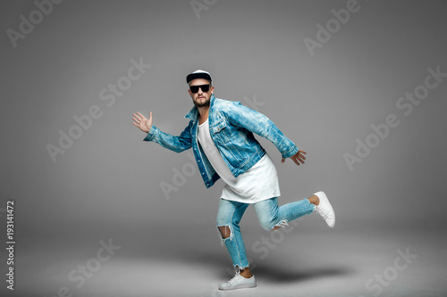 a man in a shirt lies horizontally on a white cube; man in studio on gray background 