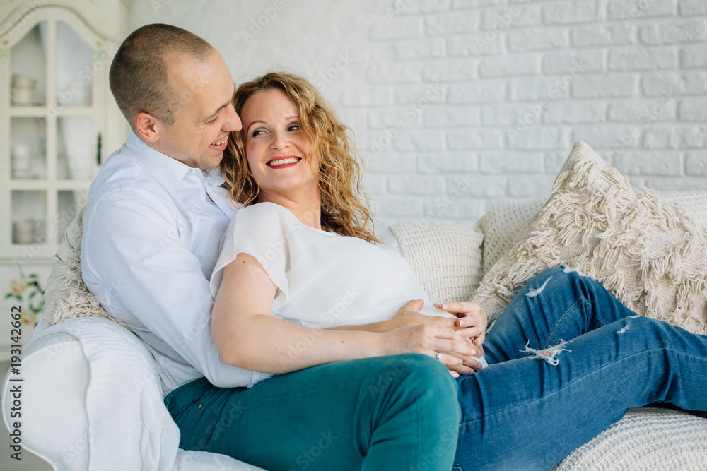 Expecting couple lying on couch in living room. Happy pregnancy concept Expecting couple lying on couch in living room. Happy pregnancy concept