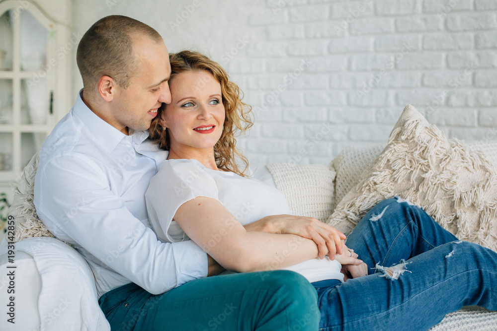 Expecting couple lying on couch in living room. Happy pregnancy concept Expecting couple lying on couch in living room. Happy pregnancy concept