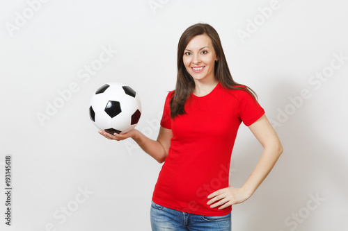Attractive European young cheerful smiling woman, football fan or player in red uniform holding soccer ball isolated on white background. Sport, play football, cheer, healthy lifestyle concept.