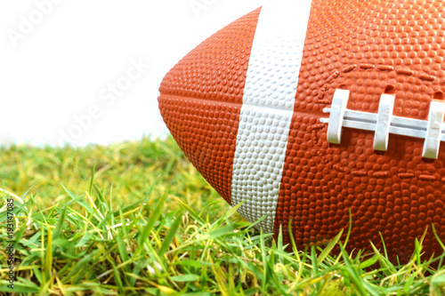American Football ball on green grass isolated on white background