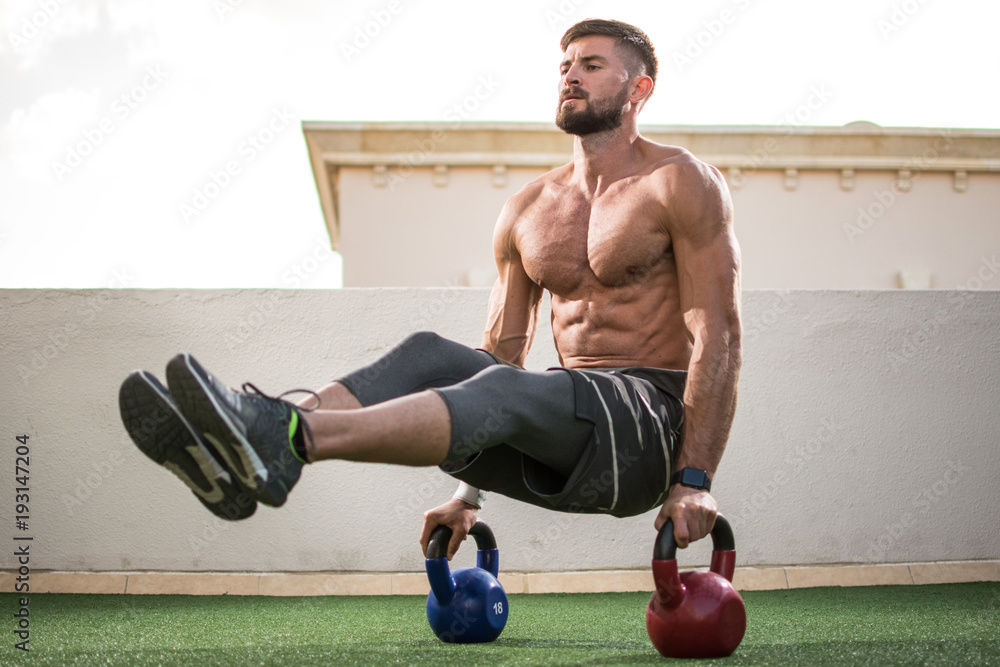 Muscular shirtless man workout with kettle bells in L Sit position at  rooftop gym. Stock Photo | Adobe Stock