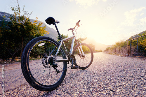 Healthy lifestyle. Close up of mountain bicycle on the road against sunny sky.