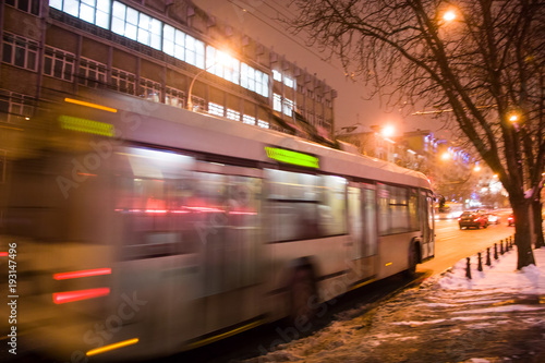 The motion of a blurred trolleybus on the street in the evening in the winter