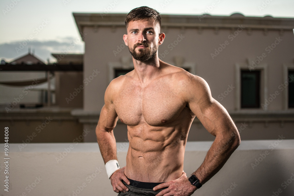 Fototapeta premium Sexy athletic man showing muscular body and six-pack abs outdoors.