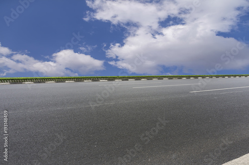 Asphalt pavements and square floor tiles under the blue sky and white clouds