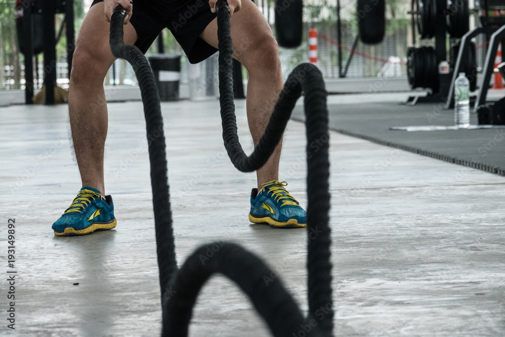 Naklejka premium Fitness trainner show how to play the sport rope equipment in the gym