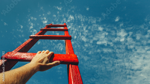 Development Attainment Motivation Career Growth Concept. Mans Hand Reaching For Red Ladder Leading To A Blue Sky