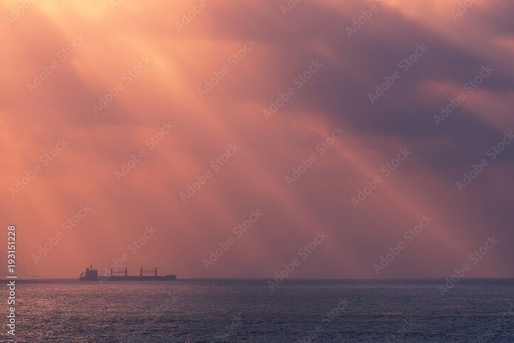 sunrays on the ocean with freighter ship