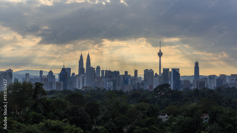 Beautiful aerial view of Kuala Lumpur city skyline, skyscraper during sunrise with dramatic sky, clouds and sun rays.