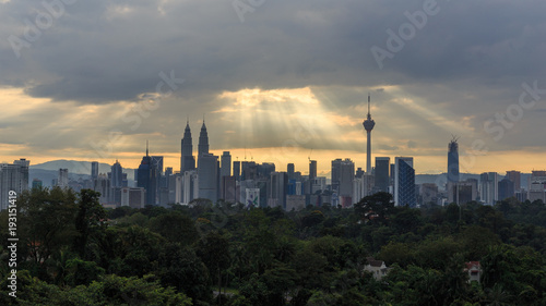 Beautiful aerial view of Kuala Lumpur city skyline, skyscraper during sunrise with dramatic sky, clouds and sun rays.