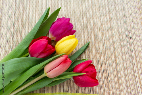 Fototapeta Naklejka Na Ścianę i Meble -  bouquet of colored tulips on a bamboo surface