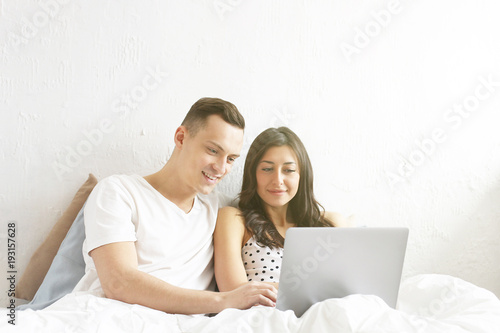 Young couple watching tv show, reading a message. Technology & relationship concept. Modern romance troubles. Male & female online dating app. Laptop, chatting, shopping, browsing, surfing.