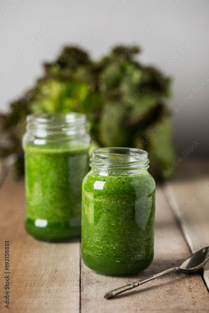 Green spinach juice jar on a rustic wooden table and spoon Green spinach juice jar on a rustic wooden table and spoon