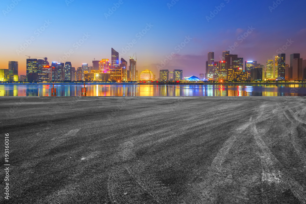 View of the skyline of Hangzhou urban architectural landscape from square floor tiles and empty asphalt pavement View of the skyline of Hangzhou urban architectural landscape from square floor tiles and empty asphalt pavement