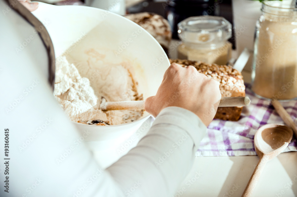 Close-up on the hand of a woman preparing a dough for homemade bread. Photo taken in the light of natural sun and studio lamps. It contains delicate artistic noise and a vintage color grading Close-up on the hand of a woman preparing a dough for homemade bread. Photo taken in the light of natural sun and studio lamps. It contains delicate artistic noise and a vintage color grading