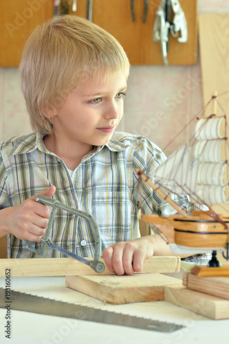 boy with model of ship and handsaw