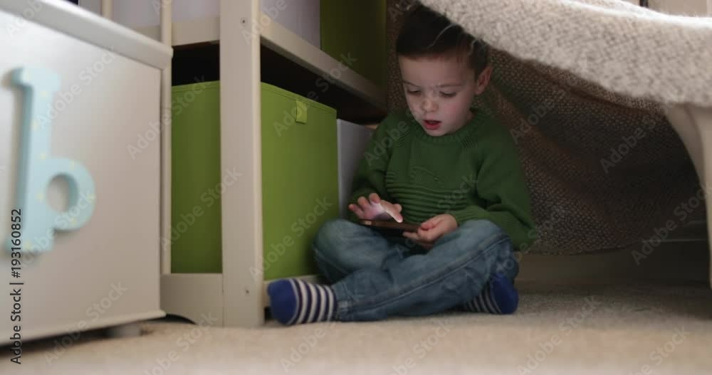 Preschool boy playing with smartphone in den Preschool boy playing with smartphone in den