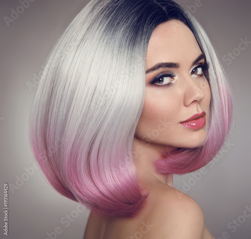 Colored Ombre bob hair extensions. Beauty makeup. Attractive Model Girl blonde with short pink hairstyle isolated on gray background. Closeup woman portrait.