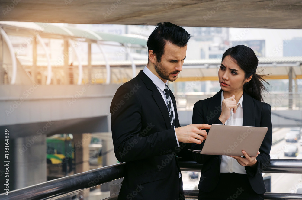 two business asian woman and caucasian man in suit talking and reading information about finance news in laptop computer in modern city, network technology, internet, successful and teamwork concept two business asian woman and caucasian man in suit talking and reading information about finance news in laptop computer in modern city, network technology, internet, successful and teamwork concept
