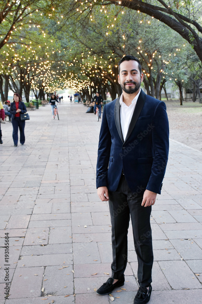 confident businessman in suit standing in a park with bokeh lights in trees