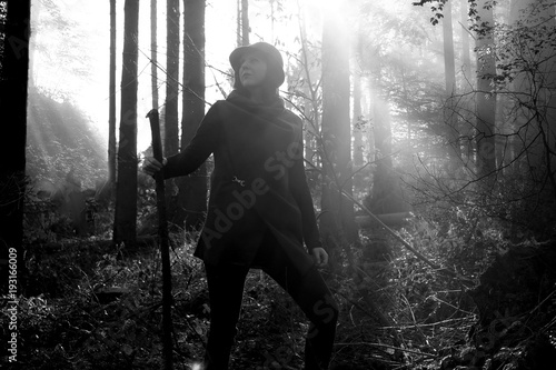 Adventure woman with a wooden rod in a forest