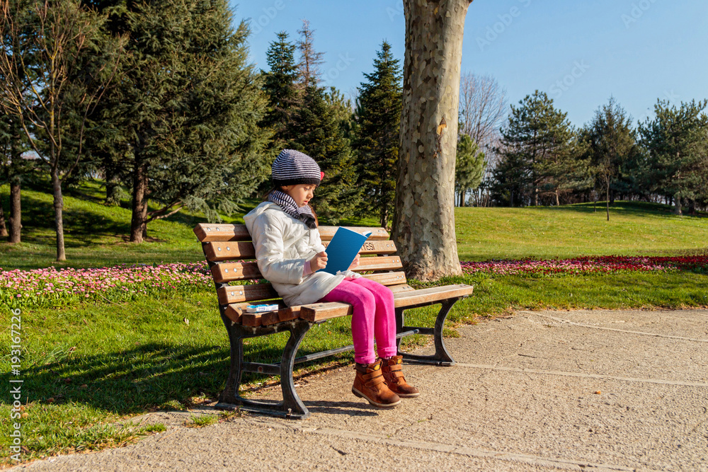 Child reading the book outdoors in the park
